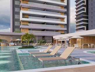 Vista do Parque das Águas do Villaggio Jardins, com espreguiçadeiras na piscina, palmeiras, áreas de convivência e os modernos edifícios ao fundo.