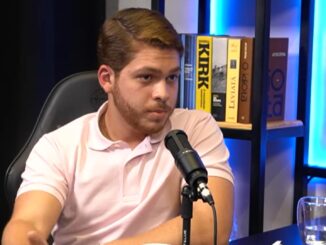 Marcelo Neto sentado em estúdio, falando no microfone durante gravação de podcast.