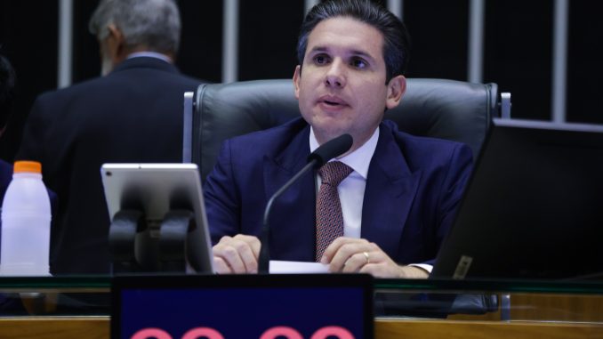 Homem de terno e gravata fala ao microfone durante sessão no plenário da Câmara dos Deputados.