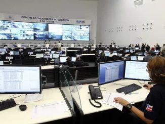 Sala do Centro de Operações e Inteligência da Bahia com profissionais monitorando ocorrências em computadores e telões.