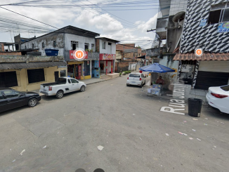 Cruzamento de ruas com comércios, carros estacionados e barraca de rua na localidade de Bate Coração, no bairro de Paripe, em Salvador.