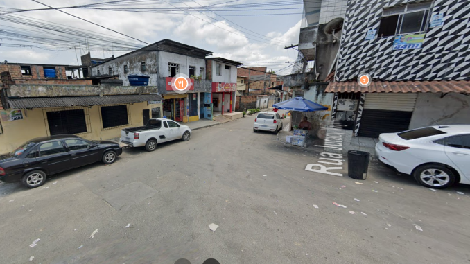 Cruzamento de ruas com comércios, carros estacionados e barraca de rua na localidade de Bate Coração, no bairro de Paripe, em Salvador.