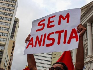 Pessoa segura cartaz escrito “Sem Anistia” em protesto de rua