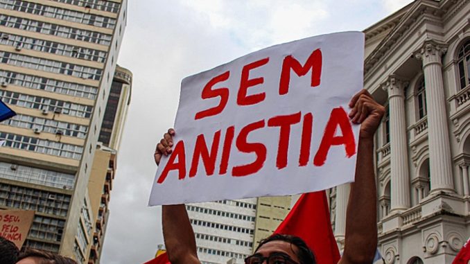 Pessoa segura cartaz escrito “Sem Anistia” em protesto de rua
