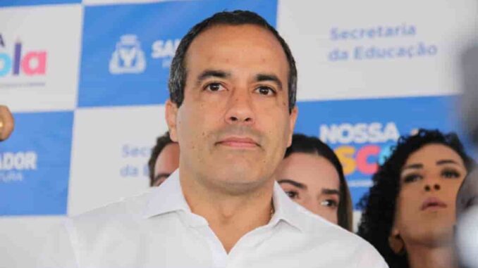 Prefeito de Salvador participa de evento oficial da gestão municipal Prefeito de Salvador em evento institucional da prefeitura, diante de painel com logotipos da gestão municipal.