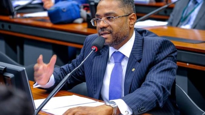 O deputado federal Márcio Marinho fala ao microfone durante sessão na Câmara dos Deputados, vestindo terno risca de giz e gravata azul.