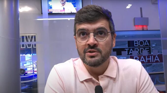 Homem de óculos e camisa polo rosa fala em entrevista no estúdio do programa Boa Tarde Bahia.