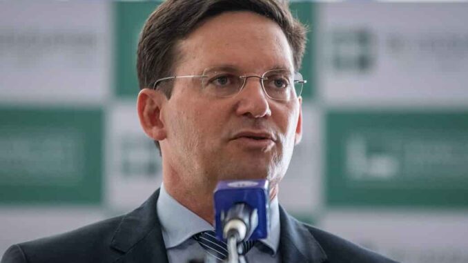 João Roma da Rádio Sociedade Homem de terno e gravata fala em microfone durante entrevista coletiva.