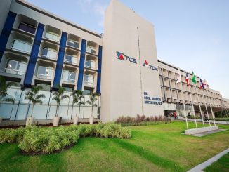 Fachada do prédio do Tribunal de Contas do Estado da Bahia, com bandeiras hasteadas e jardim na entrada.