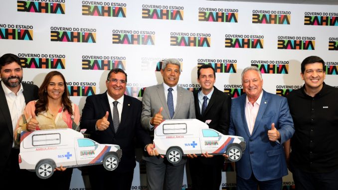 Governador Jerônimo Rodrigues posa ao lado do prefeito Tony Linhares e outras autoridades segurando placas simbólicas de ambulâncias durante entrega em Salvador.