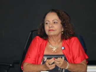 A vereadora Aladilce Souza, de blazer vermelho, sentada à mesa durante uma audiência pública em Salvador.