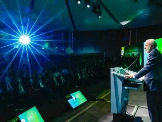 Fotografia do presidente Lula falando ao microfone durante viagem oficial.