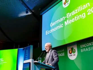 O presidente Lula fala ao microfone durante coletiva de imprensa em ambiente interno.