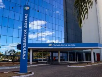 Mãos de um atendente e de um cidadão sobre um balcão com documentos previdenciários.