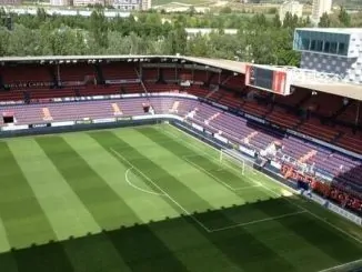 Vista do gramado e arquibancadas do Estádio Reyno de Navarra sob luz do dia.