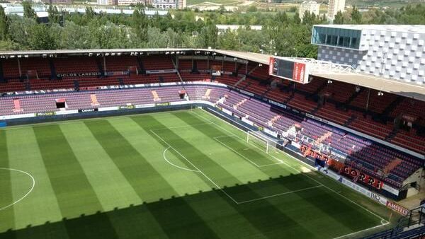 Vista do gramado e arquibancadas do Estádio Reyno de Navarra sob luz do dia.